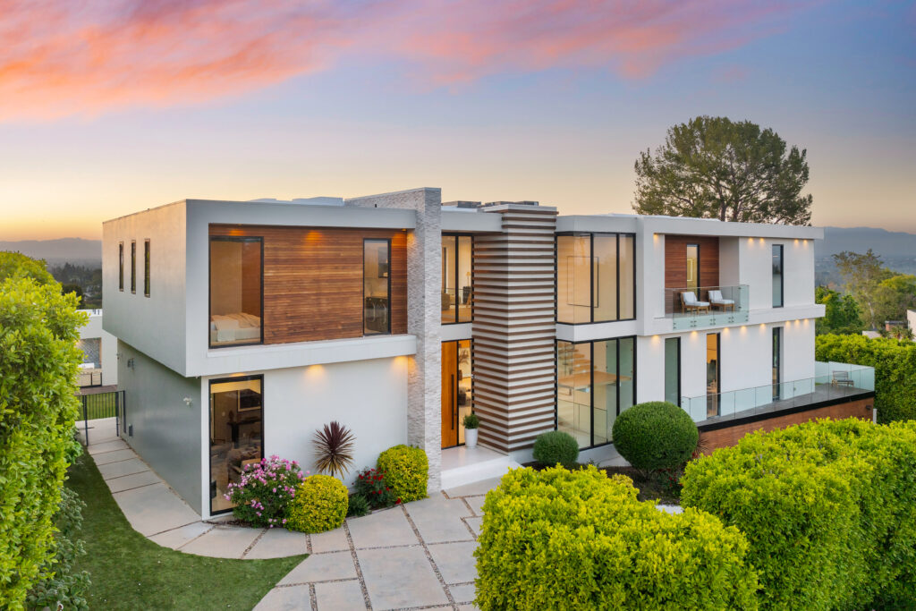 contemporary two level home on hillside with shrubs and trees